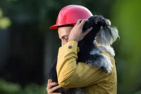 firefighter carrying dog over shoulder
