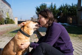 dog licking woman's face outdoors