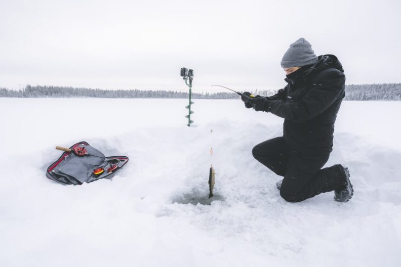 Man ice fishing on frozen lake, like one where two fishermen and dog were rescued from the ice.