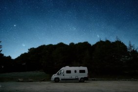 A campervan parked in a forested area in the evening, the Minneapolis shooting of a man and his dog inside a camper is under investigation.