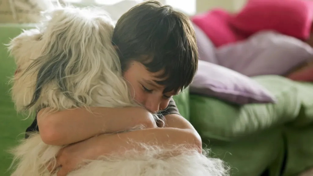 A young boy hugging his dog.
