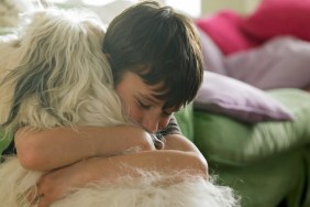 A young boy hugging his dog.