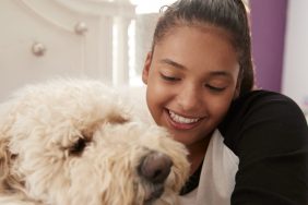 A Labradoodle dog with a girl, like the dog who became the 22nd therapy dog introduced in West Virgina schools.