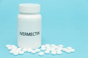 Ivermectin for dogs in white bottle packaging with scattered pills.