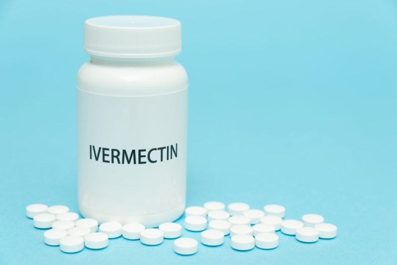 Ivermectin for dogs in white bottle packaging with scattered pills.