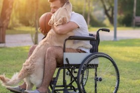Happy Man in wheelchairs is playing with his service dog