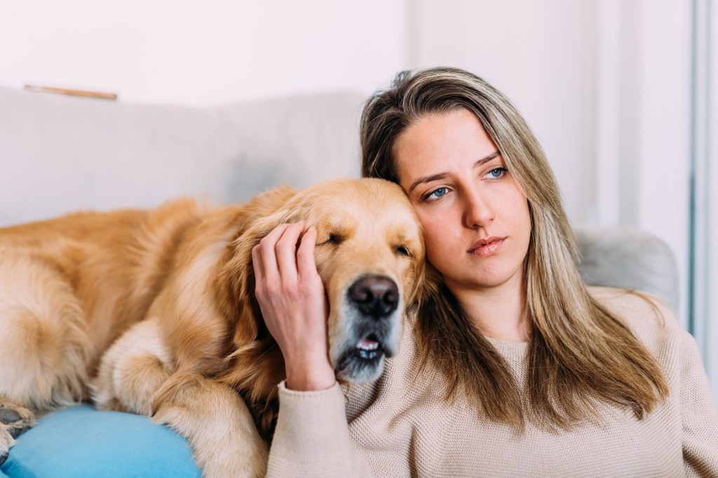 Young woman with dog at home after watching a sad movie.