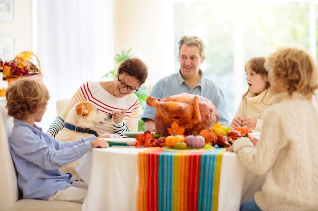 Famille et animal de compagnie au dîner de Thanksgiving, avec de la dinde sur la table.