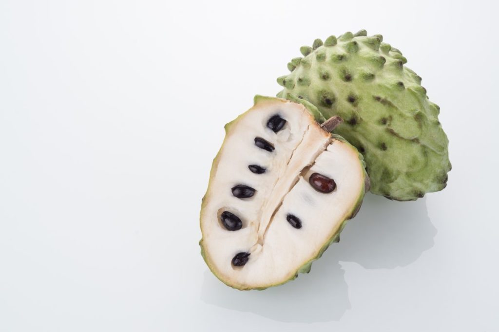 Halved Green Custard Apple/Cherimoya on White Glass Background.