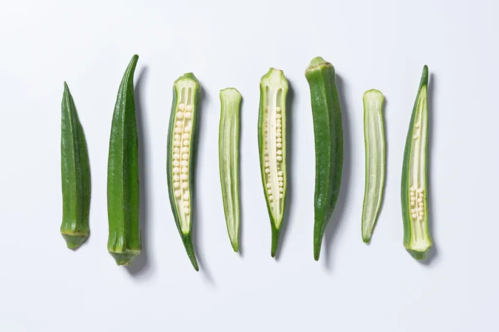 Sliced okra, which is safe for dogs to eat, against a white background.