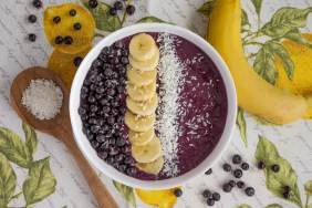 An overhead photo of an acai berry bowl, topped with coconut flakes, banana slices, and acai berries, which are not safe for dogs to eat.