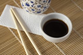 Oriental style table with soy sauce, chopsticks, napkin and ceramic cup.
