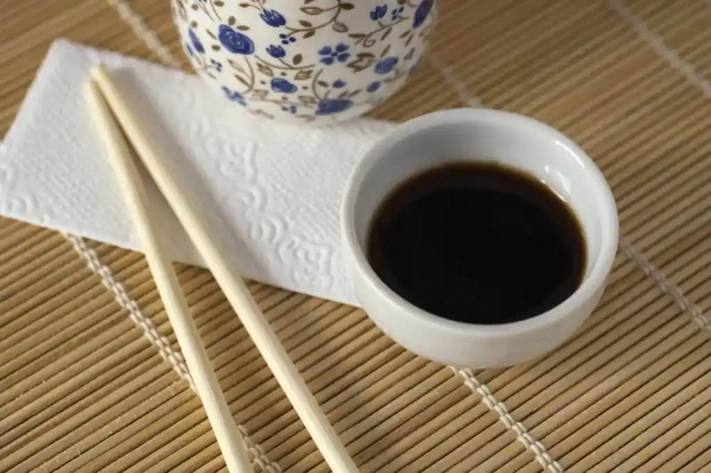 Oriental style table with soy sauce, chopsticks, napkin and ceramic cup.