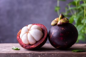 A closeup photo of a mangosteen fruit split in half, which dogs can eat with proper preparation.