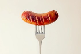 A closeup photo of cooked sausage, which dogs can eat safely if it's cooked and doesn't contain seasonings like garlic or onion, on a fork.