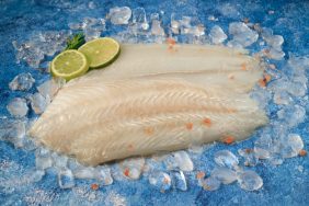 Raw sliced flounder on ice with two lime wedges.