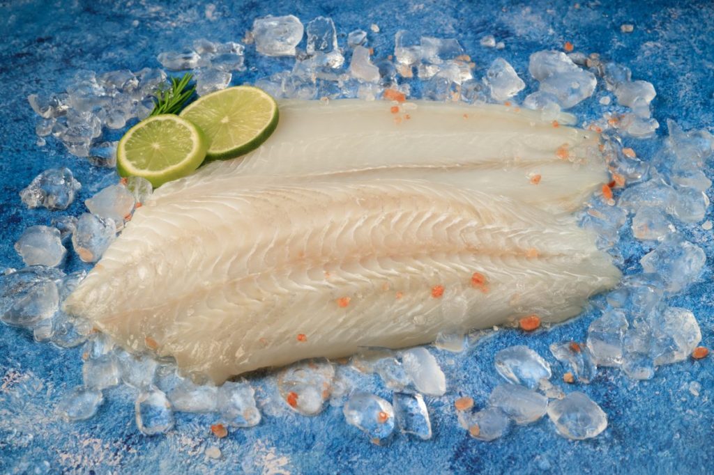 Raw sliced flounder on ice with two lime wedges.