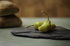 Two Pepperoncini Peppers on slate rock with wood background