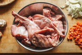 Pieces of raw rabbit meat in a bowl on kitchen table.
