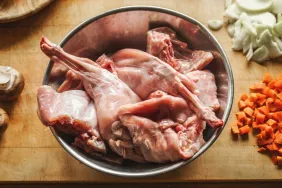 Pieces of raw rabbit meat in a bowl on kitchen table.